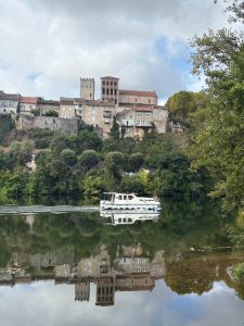 Boat slowly cruising along the Lot River near Cahors, heading toward medieval villages in the Lot Valley.