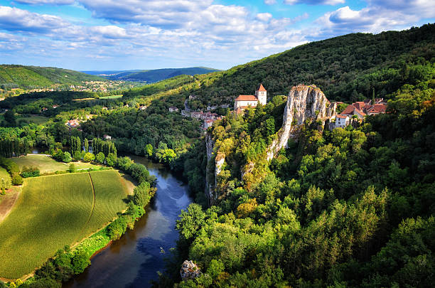 Lot River curving below the hilltop village of Saint‑Cirq‑Lapopie, with medieval houses overlooking the valley.