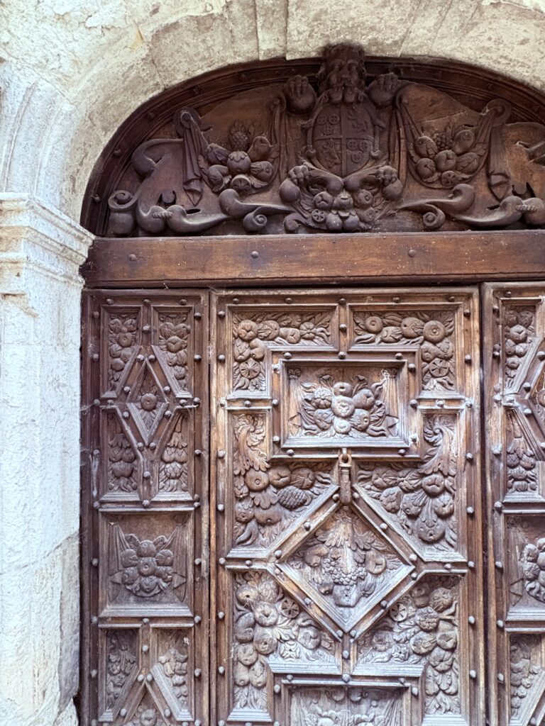 Carved wooden medieval door of one of Cahors’ oldest buildings, framed by a stone arch and once opening into a historic high‑end residence.