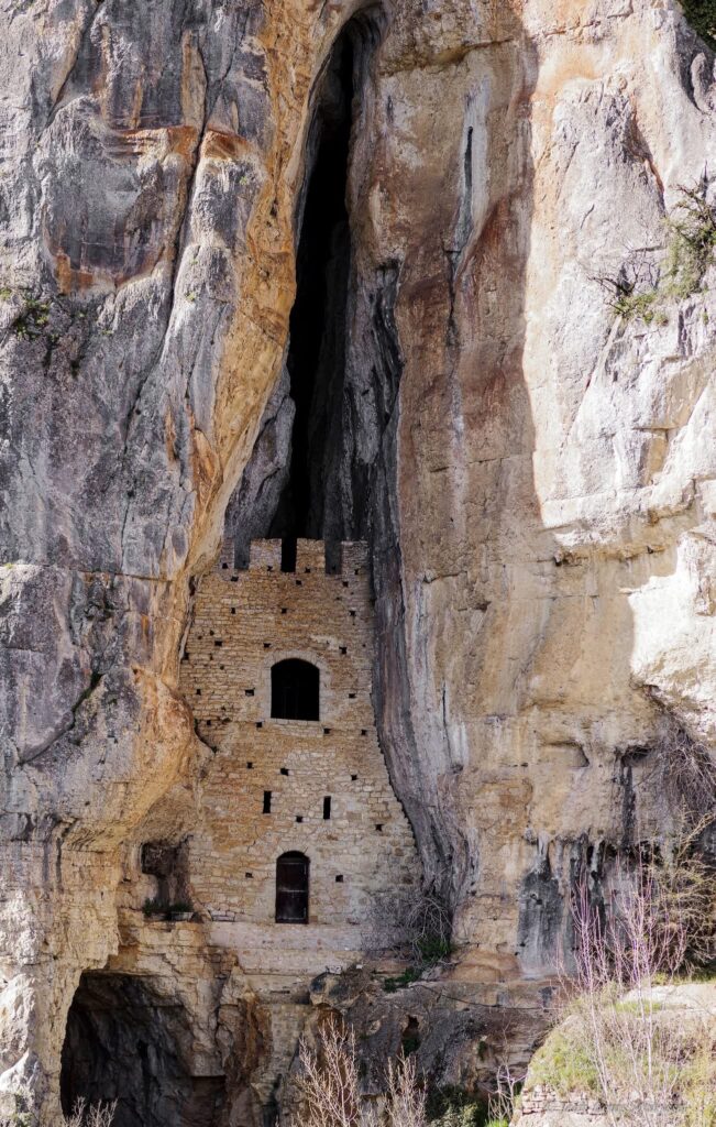 Rockshelter in Rocamadour carved into the limestone cliffs, showing natural formations above the valley.