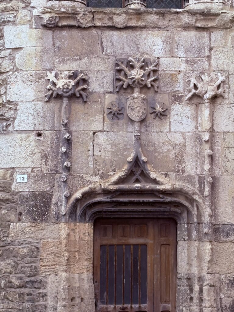 Medieval wooden door of a historic building in Cahors, framed by carved stone and centuries‑old architecture.